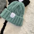 Chunky knit beanie detail showing soft mint green wool texture and stitched label design. - M (56-58cm) / Tender Bud Green