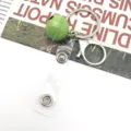 Detailed view of the green bell keychain showcasing metal ring, dog clip and transparent strap. - Green