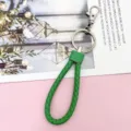 Gedetailleerd overzicht van groene gevlochten lederen sleutelhanger band, metalen ring en haakje - Omwikkeld Lederen Touw / Groen