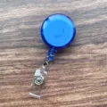 Blauwe intrekbare badgehouder met transparante strap en metalen clip voor kantoor ID. - Middelblauwe doorschijnende intrekbare badgehouder (met clip)