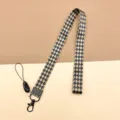 Cordón ancho con patrón de rombos y cierre metálico, ideal para tarjeteros y teléfonos. - Cuadros Negro y Marrón / Cordón Largo