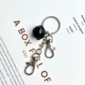 Black bell keychain with double lobster clasps, stylish metal key ring variant accessory. - Black
