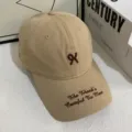 Gedetailleerde close-up van beige katoenen honkbalpet met bruin geborduurd logo en randtekst. - M / Khaki