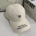 Detail van een beige katoenen honkbalpet met borduursel en tekstontwerp op de klep. - M / Broken Wit