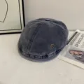 Detailed view of the retro washed denim newsboy cap, showing fine stitching and metal badge. - M (56-58cm) / Navy Blue