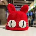 Detailed view of the cute red knit hat with cat ears and big eyes, soft winter wear. - M (56-58cm) / Red