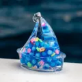 Vue détaillée d'une bouteille de sable mouvant en acrylique transparent avec perles et fleurs. - Bleu