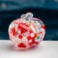 Gros plan d'un ornement de sablier en forme de pomme transparente avec des perles rouges. - Rouge