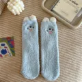 Detail view of fluffy blue fuzzy socks with cute three-eyed monster design for cozy winter home. - One Size / Blue Gold