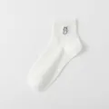 Nahaufnahme von kurzen weißen Baumwollsocken mit einer süßen grauen Katzenstickerei. - Einheitsgröße / Weiß