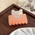 Pince à cheveux française en résine rose pêche avec nœud irisé et strass pour coiffure élégante. - Orange