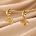 Close-up detail of exquisite gold four-leaf clover drop earrings hanging on a thin wooden stick. - Four Leaf Clover Style (E7065)