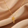 Primo piano della delicata collana con ciondolo a palma dorata su sfondo in tessuto serico. - Stile Cocco Minimalista a Strato Singolo (N08360G)