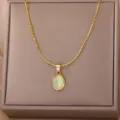 Detailed view of the gold tone necklace with oval green stone pendant in a jewelry box. - Gold Green Cat's Eye Stone Style