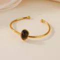 Closeup view of the gold-tone stainless steel cuff bracelet featuring a teardrop natural stone. - Waterdrop Brown Stone Style (B2040G-3)