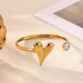 Close-up of gold stainless steel open bangle bracelet with heart charm and clear rhinestone. - Solid Heart Style (B2284G)