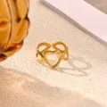 Close-up detail of the gold-plated stainless steel hollow heart open ring on textured background. - Hollow Heart Style (JZ9698G)