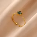 Close-up view of gold-plated stainless steel twisted ring with green rhinestone flower detail. - Open Ring / Green