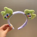 Primer plano detallado de la bonita diadema de felpa de rana de dibujos animados verde, suave. - Gatito verde