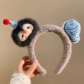 Close-up detail of the grey plush headband featuring cute cartoon animal and blue fish decors. - Penguin