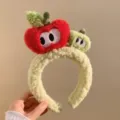 Detail du bandeau en peluche pomme douce avec une texture moelleuse et des yeux brodes. - Pomme Rouge