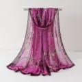 Vue détaillée d'un élégant foulard en mousseline à motif floral violet drapé sur support. - Foulards en mousseline 23