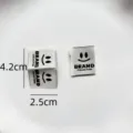Custom clothing woven labels with smiley face design, black and white apparel garment tags. - Smiley Brand