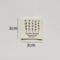 Detail view of handmade cotton clothing label with flower pattern, size 3x3cm, ideal for DIY crafts. - CM001