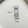 Vista dettagliata dell'etichetta tessuta con smiley e dimensioni per cucito e fai da te. - Stile Hello Sorriso Nero e Bianco (zm115)