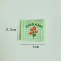 Handmade green plaid fabric label with cute orange flower embroidery for DIY sewing crafts. - Small Daisy (Green Background)