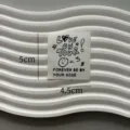 Detailed view of white fabric clothing label featuring cute letter print and smiley face design. - Love You Smiley Face