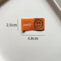 Etichetta tessuta arancione con design sorridente e testo, ideale per vestiti e accessori fai da te. - Stile SMILE Arancione (zm123)