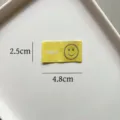 Etichetta tessuta piegata gialla con simpatico viso sorridente e testo per abbigliamento e accessori. - Stile SMILE Giallo (zm125)