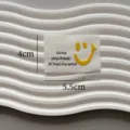 Custom clothing fabric label with smiley face and text design, ideal for garments and DIY. - Flocked Smiley Face