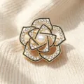 Exquisite camellia brooch detail featuring sparkling rhinestones and a central pearl inlay. - Gold Black