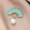 Primer plano de broche en forma de abanico estilo chino con esmalte, pedrería y perla. - Esmalte Cian