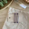 Detailaufnahme von lila transparenten tropfenförmigen Haarklammern auf Karte chic. - Nebelviolett (Paar)