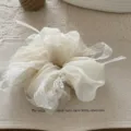 Nahaufnahme eines weißen Organza-Haargummis mit zarter Spitzenbanderole und Perle. - Gebrochenes Weiß