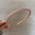 Vue détaillée du serre-tête rembourré en cuir rose, montrant sa texture douce et sa forme haute. - Rose