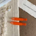Detalle pinzas de pelo de resina naranja, horquillas pico de pato, estilo flat lay. - Naranja