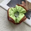 Detailed view of a stylish green hair scrunchie featuring a unique brown zipper trim. - Zipper Style / Caramel Zipper Style