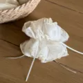 Close-up of a white sheer organza scrunchie with pearl bow detail, textured fabric. - Slim Fit Model