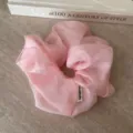 Rosa Organza Haargummi Detailaufnahme mit weicher Netzstruktur und filzigem Label. - Rosa