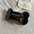 Detailed view of a cute black hair claw clip featuring white polka dots and a playful bone shape. - Large Bone Hair Claw / Black Polka Dot