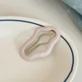 Close-up detail of a cute pink wavy fabric hair clip resting on a white ceramic plate. - Pink Cloud Hair Clips