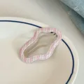 Close-up detail shot of a pink and white plaid wavy hair clip on a white ceramic plate. - Striped Cloud Clip