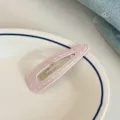 Close-up of a sweet pink polka dot snap hair clip on a white ceramic plate, detail. - Polka Dot Teardrop Hair Clip