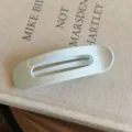 Gros plan d'une pince à cheveux ovale blanche minimaliste, mettant en valeur sa texture lisse. - L / Bleu clair