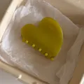 Detail view of olive green jelly heart hair claw clip presented on white tissue paper inside box. - Heart Style