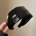 Nahaufnahme des glänzenden schwarzen breiten Lederhaarbands, elegantes alltägliches Haaraccessoire. - Schwarzes PU-Leder